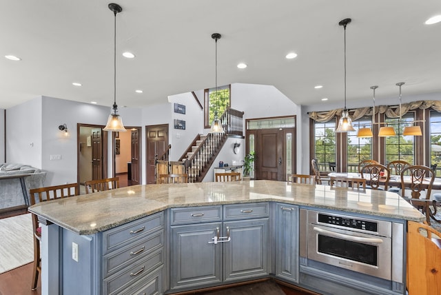 kitchen with decorative light fixtures, light stone countertops, dark hardwood / wood-style floors, and oven