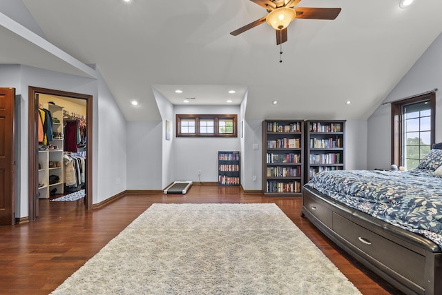 bedroom featuring vaulted ceiling, dark hardwood / wood-style floors, a spacious closet, a closet, and ceiling fan