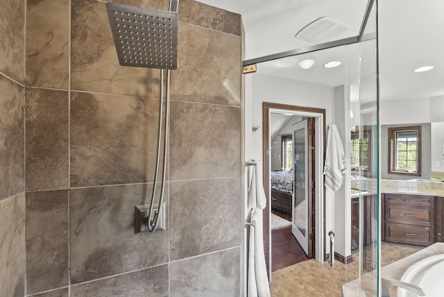 bathroom featuring tile patterned flooring, a tile shower, and vanity