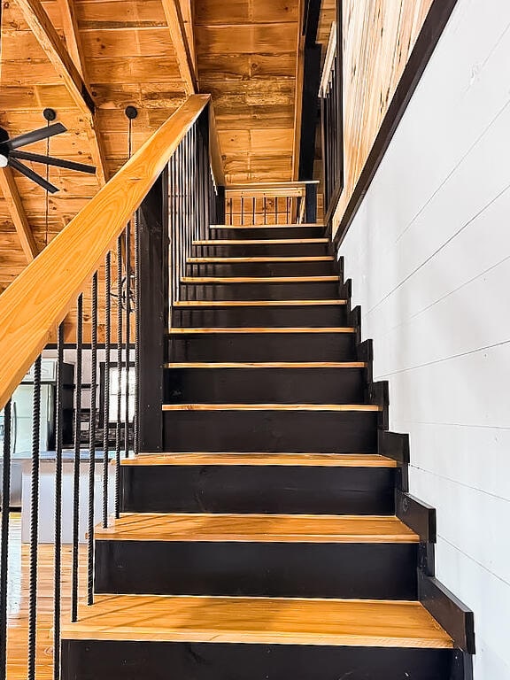 stairs with beam ceiling, wood ceiling, and wood-type flooring