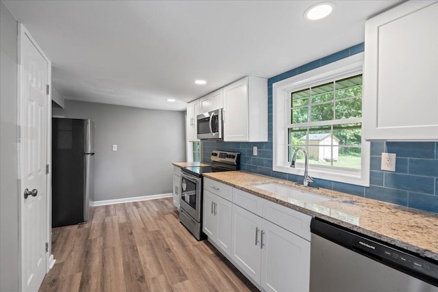 kitchen featuring light hardwood / wood-style floors, stainless steel appliances, sink, white cabinetry, and light stone counters