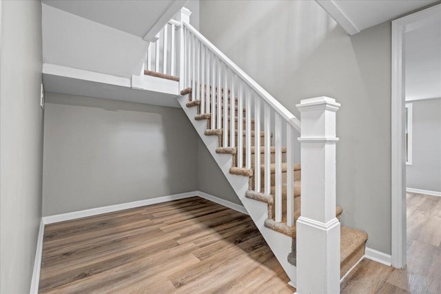 stairway with hardwood / wood-style floors and a high ceiling