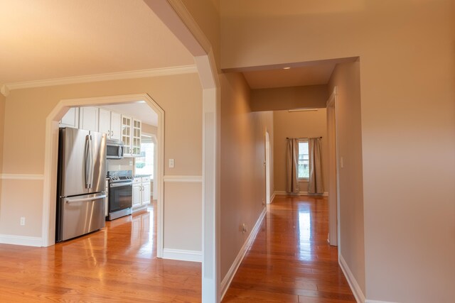 hall with light wood-type flooring and crown molding