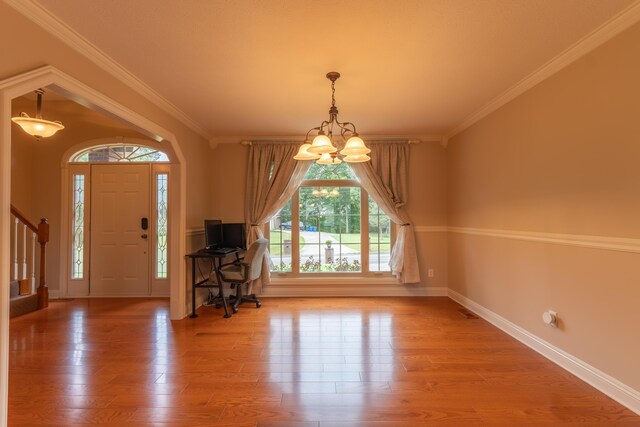 entryway with ornamental molding, hardwood / wood-style floors, and a chandelier