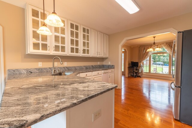 kitchen with sink, white cabinets, light hardwood / wood-style flooring, decorative light fixtures, and stainless steel fridge