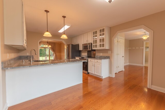 kitchen with light hardwood / wood-style flooring, white cabinets, kitchen peninsula, and sink