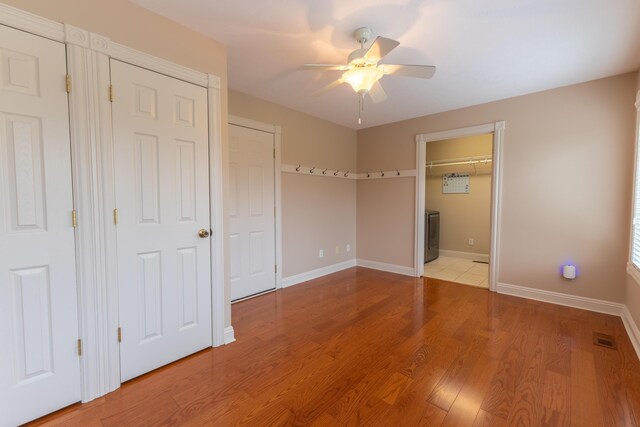 unfurnished bedroom featuring multiple closets, ceiling fan, and hardwood / wood-style flooring