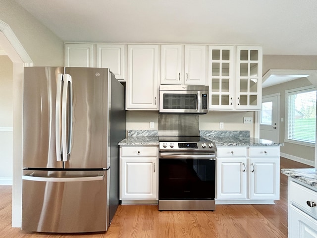 244 Water Cliff Dr, Somerset, KY 42503 - kitchen with glass insert cabinets, light stone countertops, arched walkways, a sink, and stainless steel appliances