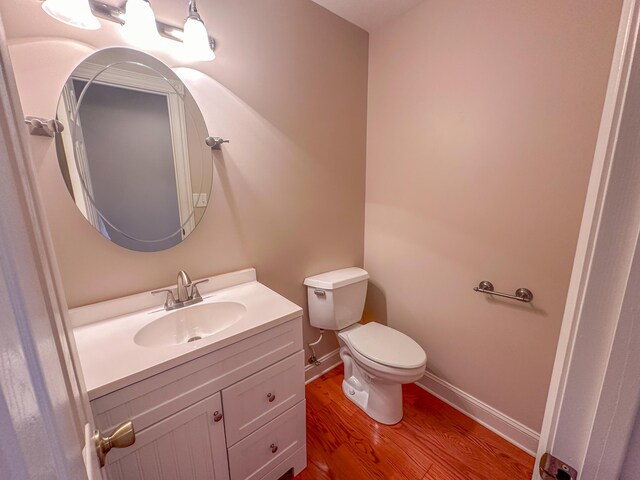 bathroom featuring wood-type flooring, vanity, and toilet