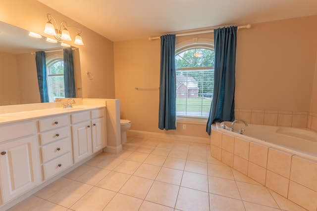 bathroom with a healthy amount of sunlight, tiled tub, vanity, and toilet