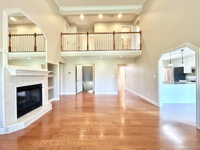 244 Water Cliff Dr, Somerset, KY 42503 - unfurnished living room with a tiled fireplace, light wood finished floors, a towering ceiling, and baseboards
