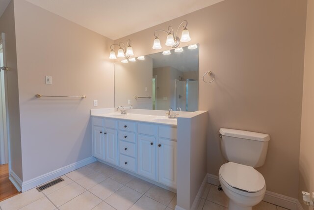 bathroom with tile patterned flooring, a shower with shower door, vanity, and toilet