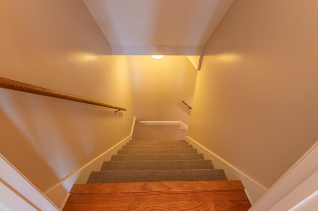 staircase featuring a textured ceiling