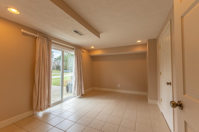 spare room featuring light tile patterned flooring and a textured ceiling