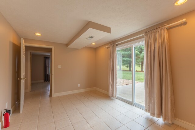 spare room with a textured ceiling and light tile patterned floors