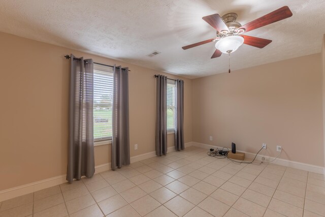 tiled spare room with ceiling fan and a textured ceiling