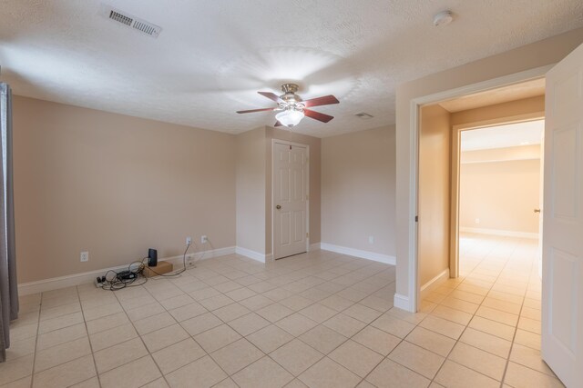 spare room with ceiling fan, a textured ceiling, and light tile patterned floors