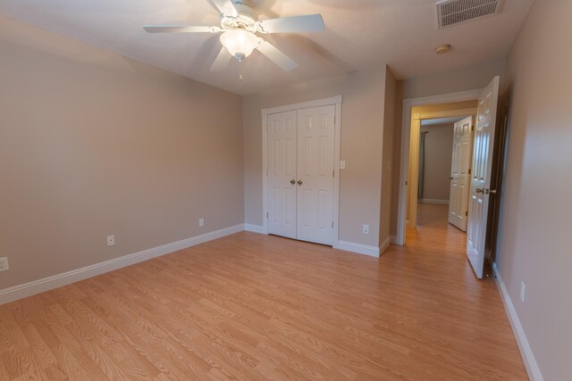 unfurnished bedroom with light hardwood / wood-style flooring, a closet, and ceiling fan