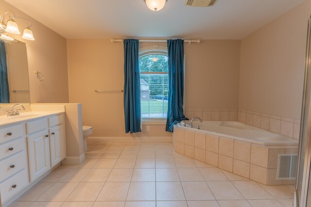 bathroom with vanity, tiled bath, tile patterned flooring, and toilet