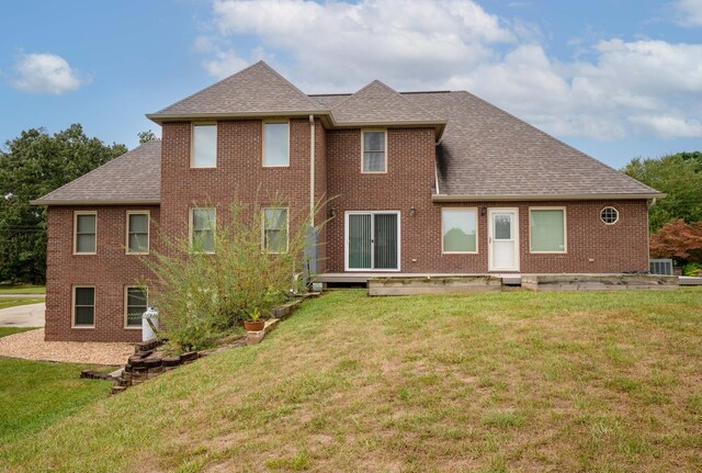 rear view of property with a lawn and central air condition unit