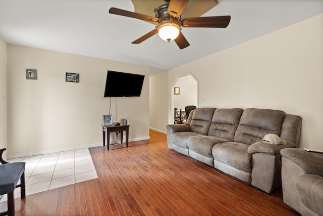 living area with hardwood / wood-style floors, ceiling fan, arched walkways, and baseboards