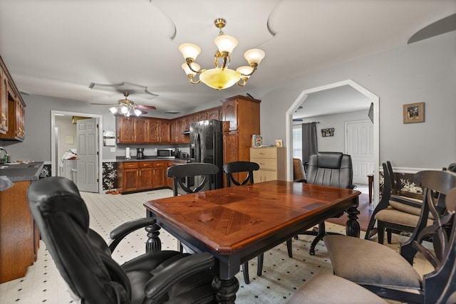 dining space featuring arched walkways, ceiling fan, a chandelier, and light floors