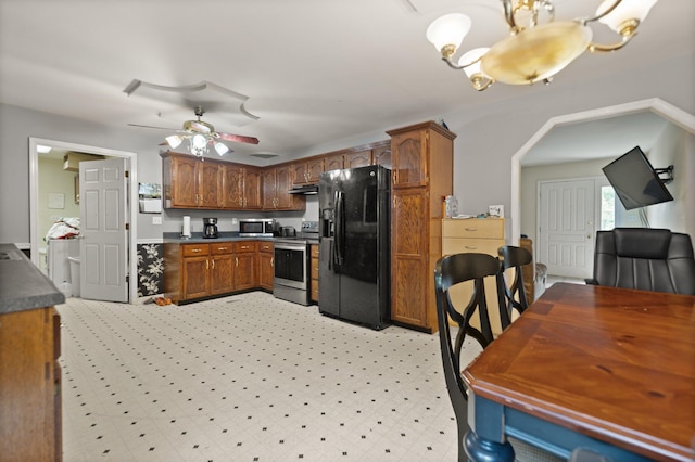 kitchen with stainless steel appliances, under cabinet range hood, ceiling fan, arched walkways, and dark countertops