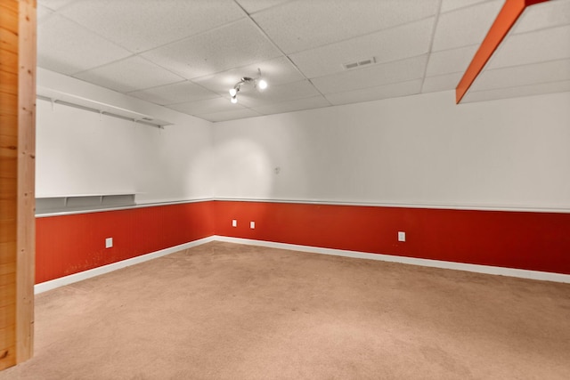 carpeted empty room featuring a drop ceiling