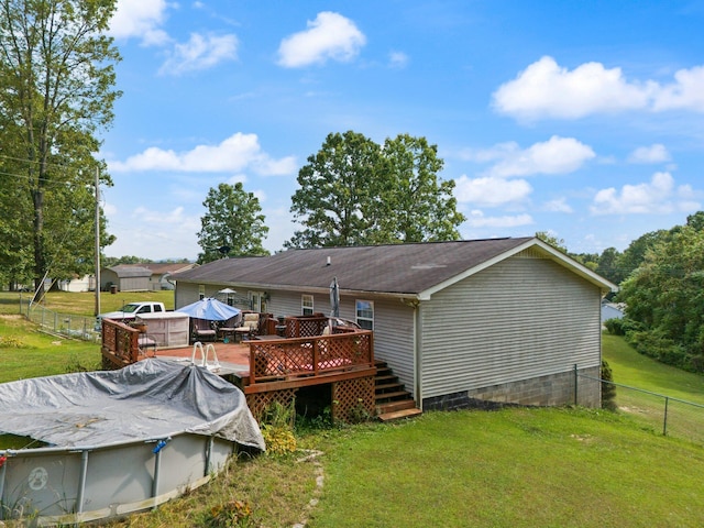 back of property featuring a deck and a lawn