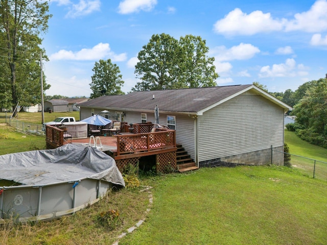 rear view of property featuring a wooden deck and a lawn