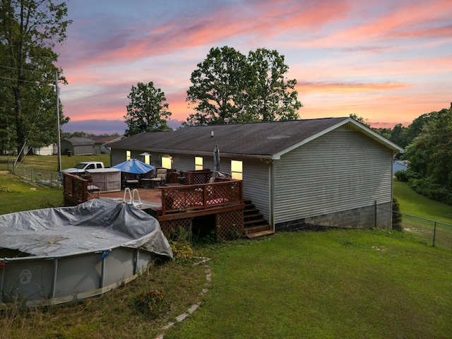 back house at dusk with a swimming pool side deck and a yard