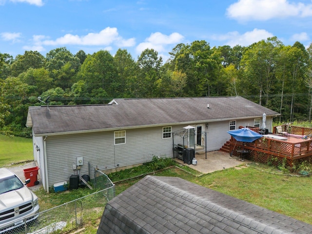 back of property featuring a wooden deck, a patio area, and roof with shingles