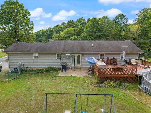 back of property featuring a wooden deck, a lawn, and a patio area