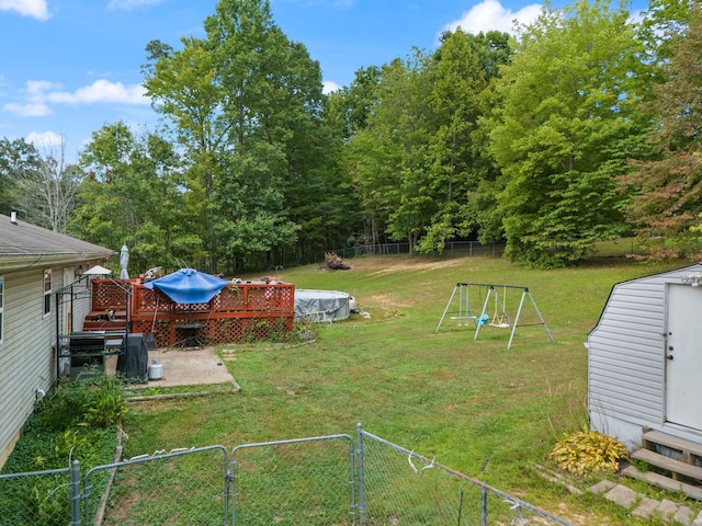 view of yard with a deck, a gate, a storage unit, an outbuilding, and a playground