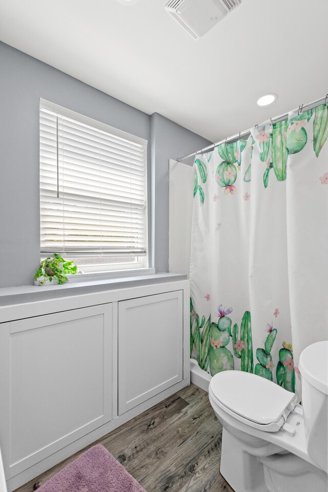 bathroom featuring toilet, hardwood / wood-style floors, and curtained shower