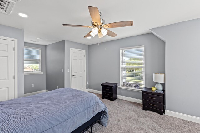 bedroom featuring multiple windows, ceiling fan, and light carpet