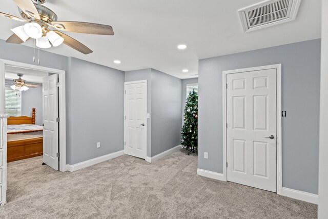 unfurnished bedroom featuring light colored carpet and ceiling fan