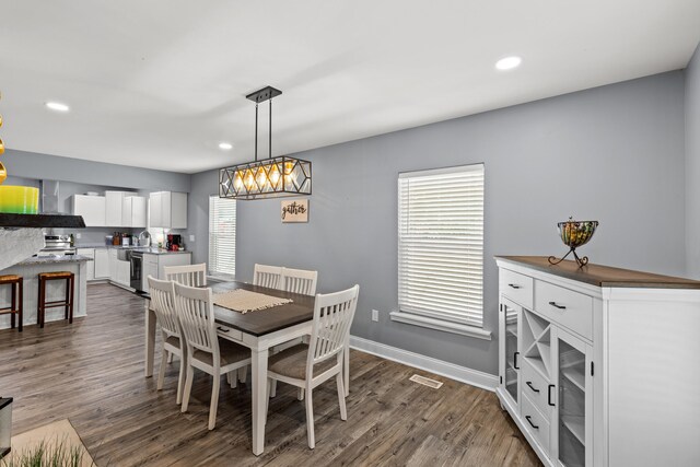 dining area featuring dark wood-type flooring, sink, and a chandelier