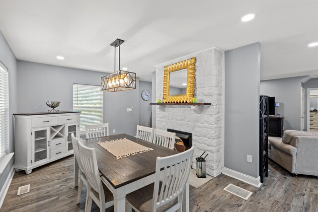 dining area featuring an inviting chandelier, wood-type flooring, and a fireplace