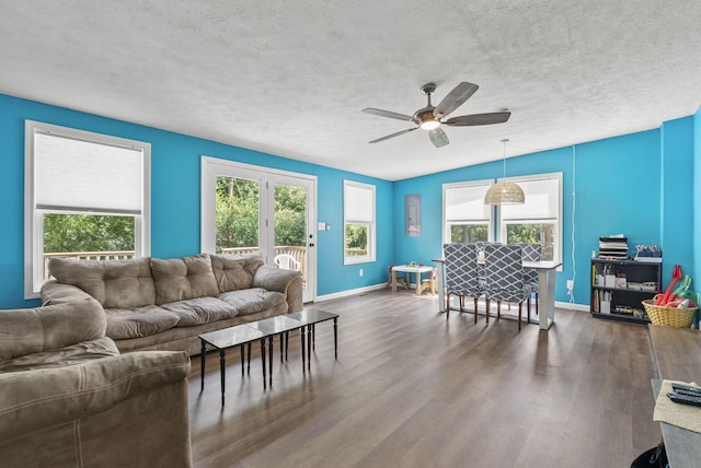 living room featuring dark wood-type flooring, ceiling fan, plenty of natural light, and a textured ceiling