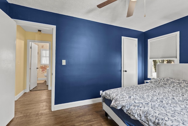 bedroom with ceiling fan, connected bathroom, dark hardwood / wood-style flooring, and a textured ceiling