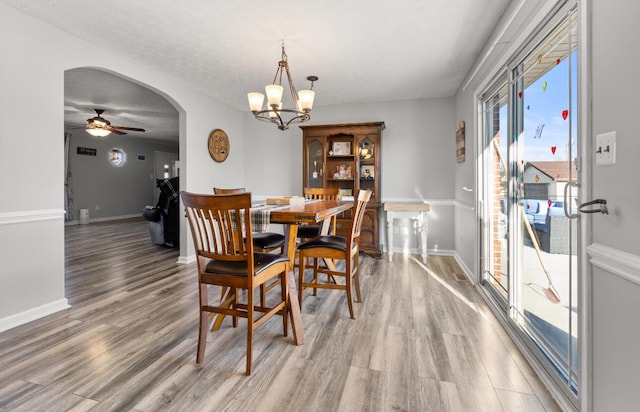 dining space with ceiling fan with notable chandelier, hardwood / wood-style flooring, and a textured ceiling