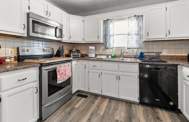 kitchen with backsplash, sink, appliances with stainless steel finishes, hardwood / wood-style flooring, and white cabinets