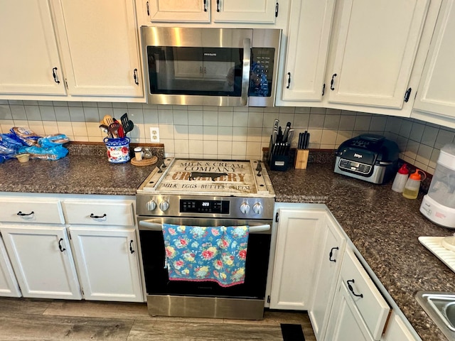 kitchen featuring white cabinetry, wood-type flooring, backsplash, and stainless steel appliances