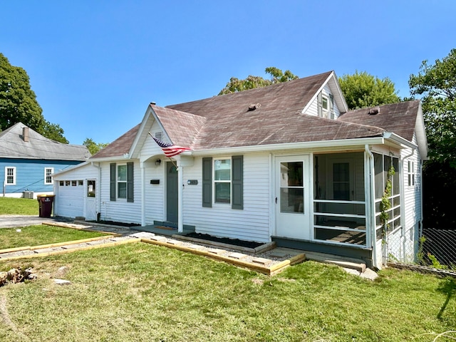 view of front of home with a garage, a front yard, and a sunroom