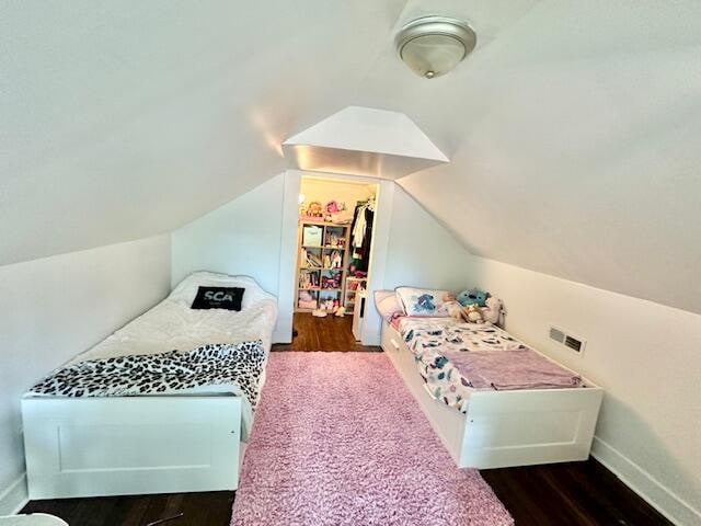 bedroom with dark hardwood / wood-style flooring, a closet, lofted ceiling, and a spacious closet