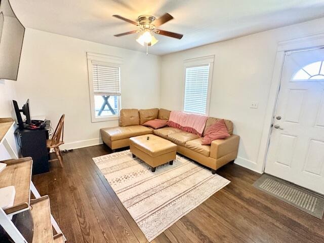 living room featuring ceiling fan and dark hardwood / wood-style floors