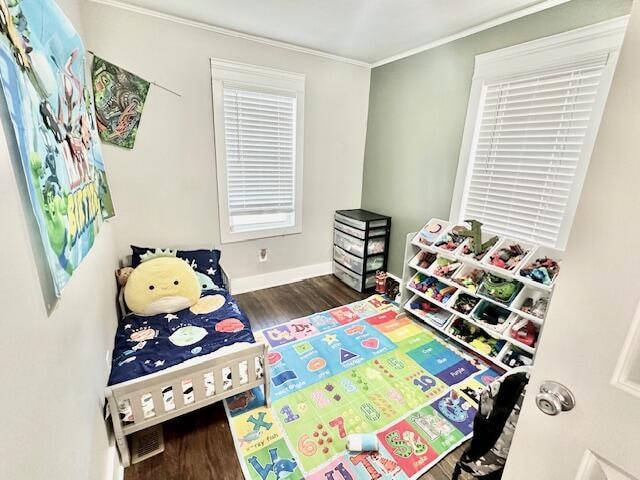 playroom with dark wood-type flooring and crown molding