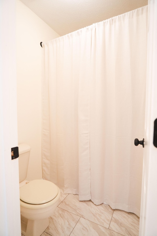 bathroom featuring curtained shower and toilet