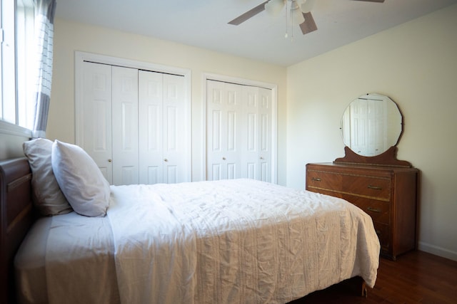 bedroom featuring dark wood-type flooring, ceiling fan, and two closets